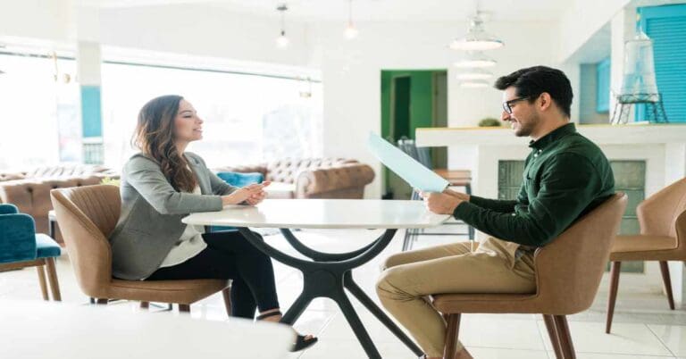 Young recruiter reviewing resume of applicant during interview at office