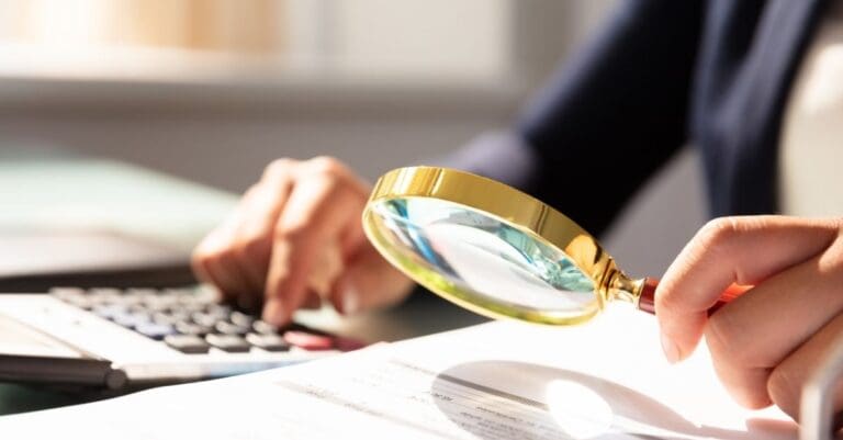Woman with a magnifying glass inspecting a financial document